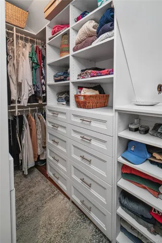 a view of walk in closet with clothes and shoes
