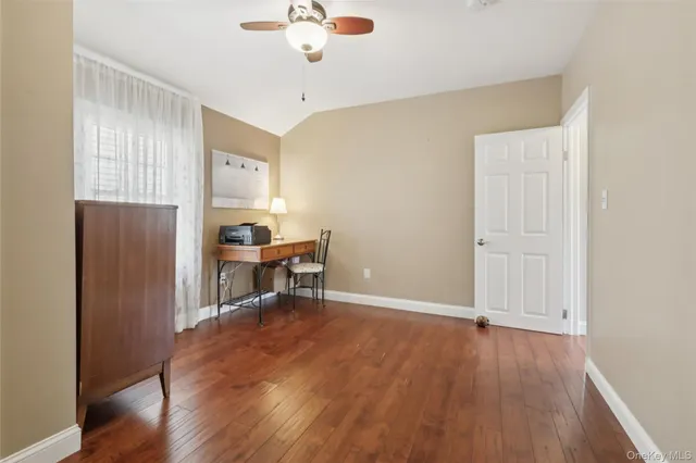 an empty room with wooden floor a chandelier fan and windows