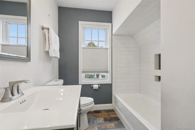 a bathroom with a bathtub shower sink mirror and toilet