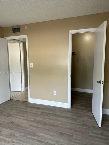 a view of an empty room with wooden floor and closet