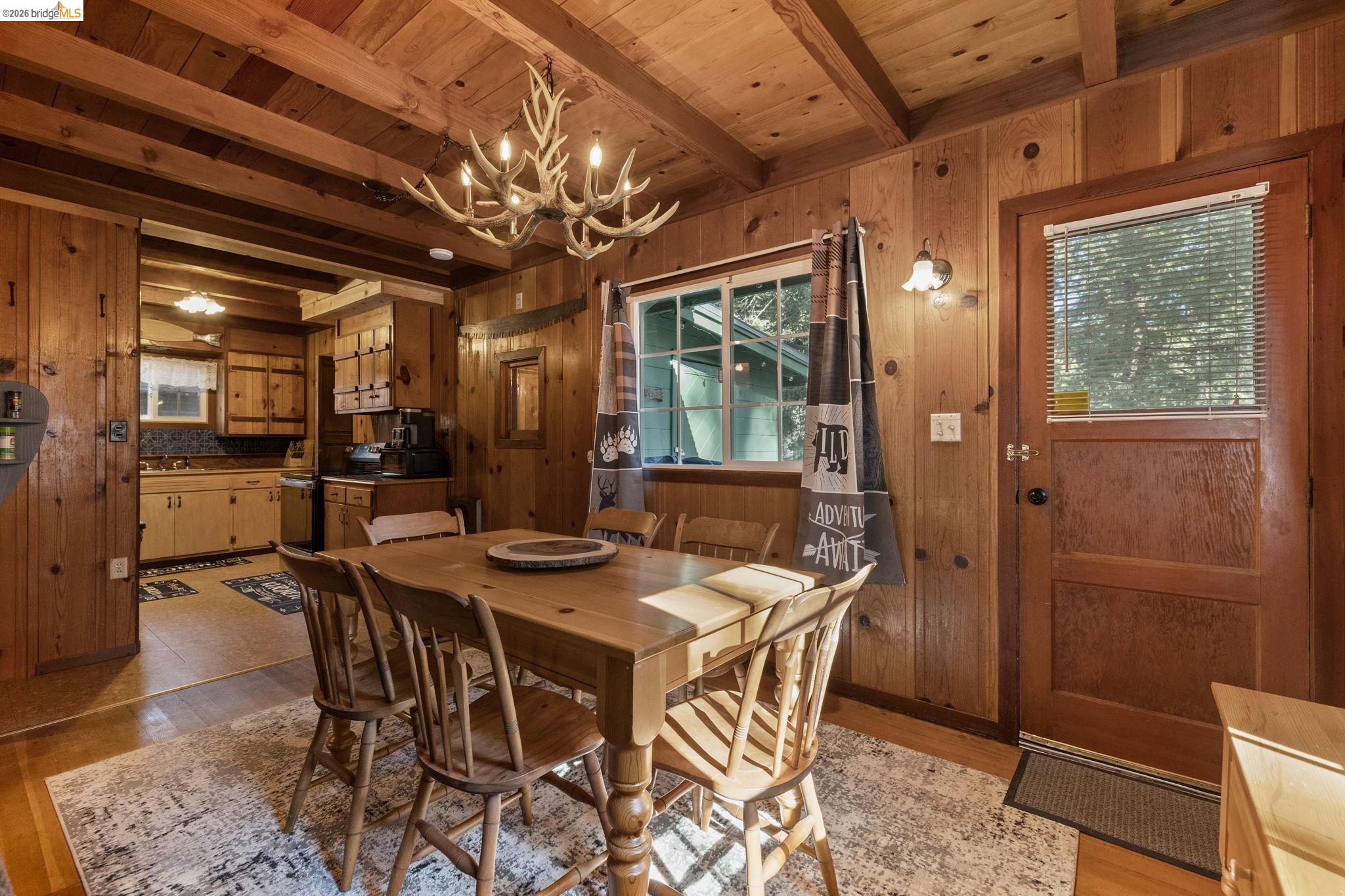 26175 Janice Way Long Barn, CA 95335 - Photo 6 of 23 Dining room with wooden walls, light wood-style floors, suspended lighting, and a wood ceiling with exposed beams