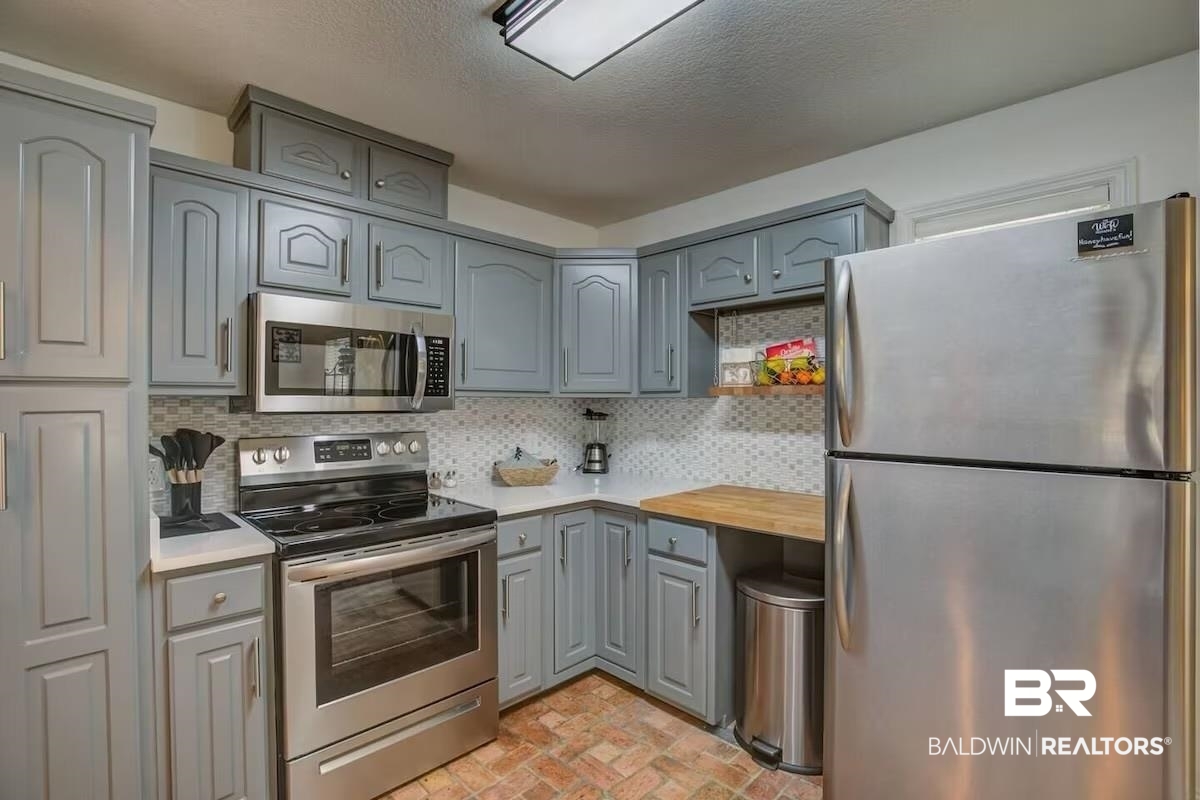 16297 Honey Road Summerdale, AL 36580 - Photo 13 of 24 Kitchen featuring light gray cabinetry, stainless steel appliances, a white tile backsplash, and light-toned countertops