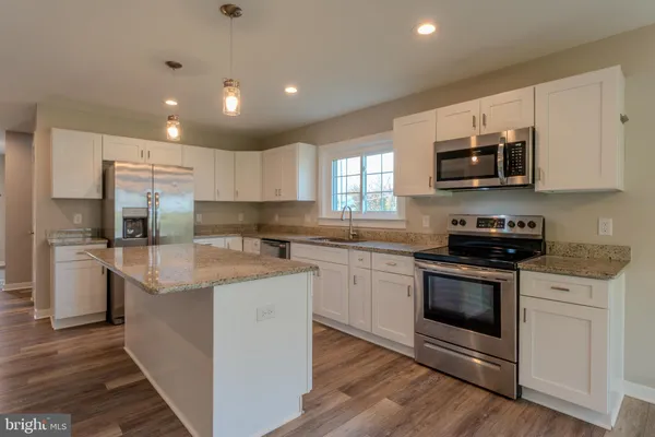 a kitchen with granite countertop a stove a sink and a microwave