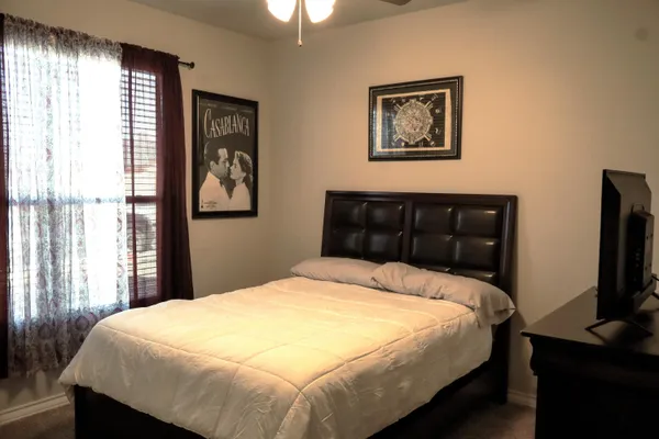 a bedroom with a bed and a flat tv screen on dresser