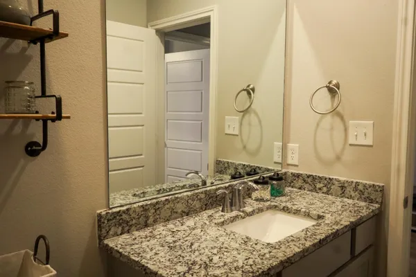 a bathroom with a granite countertop sink and a mirror