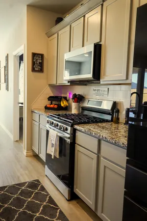 a kitchen with stainless steel appliances granite countertop a stove a sink and a microwave