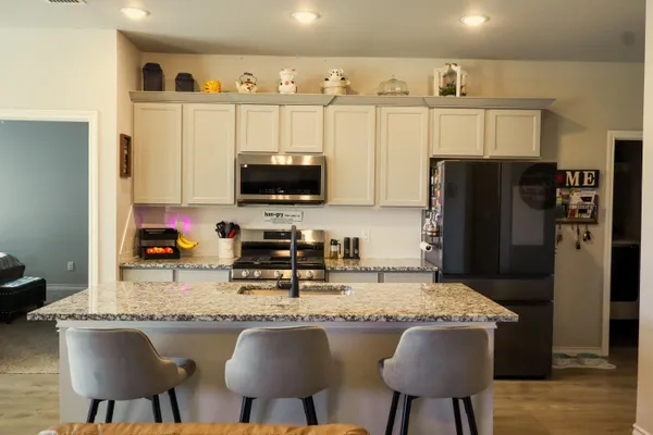 a kitchen with stainless steel appliances granite countertop a stove a refrigerator a sink a dining table and chairs