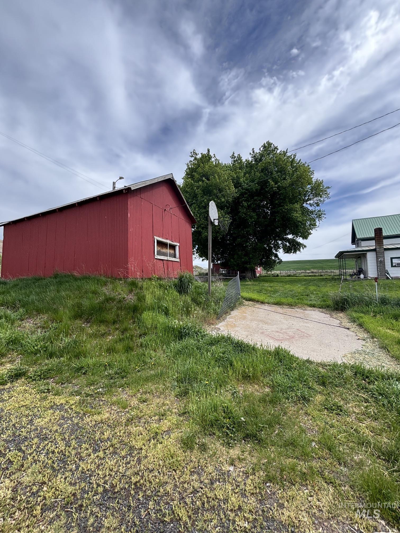 845 Malone Hill Road Pomeroy, WA 99347 - Photo 14 of 30 Red-sided outbuilding with a white-trimmed window, a gravel area, and a chain-link fence