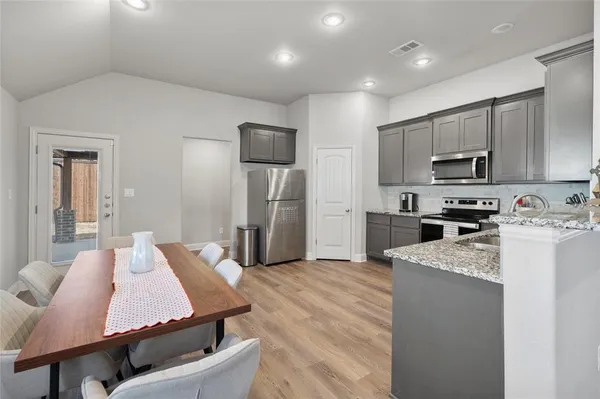 a kitchen with sink a refrigerator and a stove top oven with wooden floor