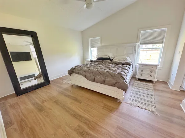 a bedroom with a bed a mirror and a flat tv screen on a dresser