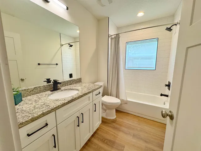 a bathroom with a granite countertop sink toilet and shower