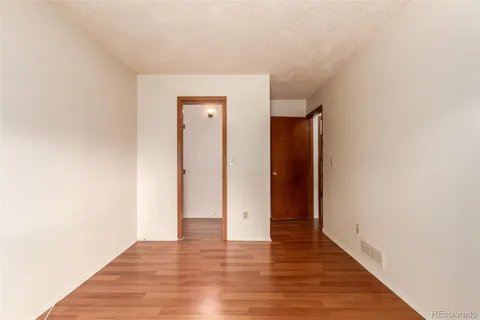 a view of an empty room with wooden floor and closet