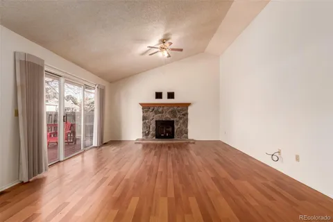 a view of an empty room with wooden floor fireplace and a window