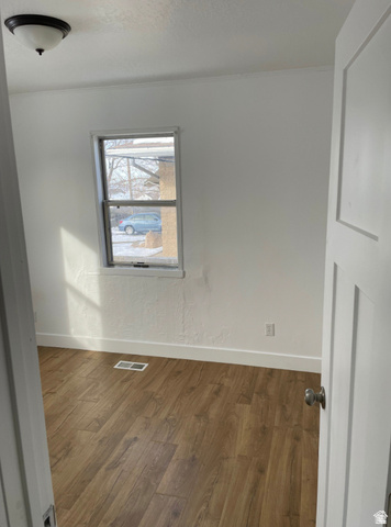 230 North 2nd Street Tooele, UT 84074 - Photo 11 of 18 Room featuring wood-finish flooring, white baseboards, a single window, and a flush mount ceiling light fixture