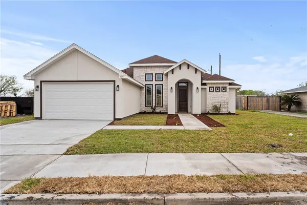 a view of a white house with a small yard and large tree