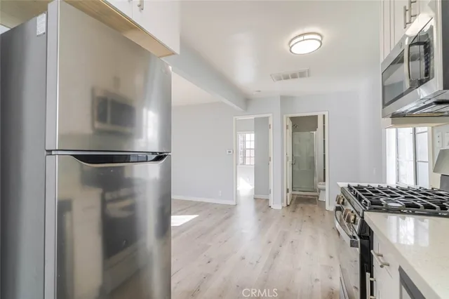 a view of a kitchen with a refrigerator and wooden floor