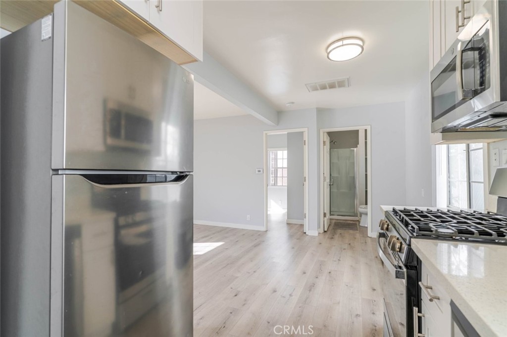 301 East Alameda Avenue, Unit A Burbank, CA 91502 - Photo 8 of 18 a view of a kitchen with a refrigerator and wooden floor