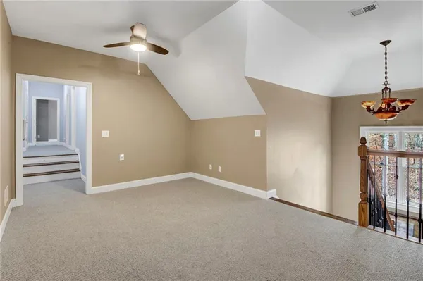 a view of an empty room with stairs and a chandelier fan