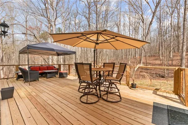 a view of a roof deck with table and chairs under an umbrella with wooden floor and a yard