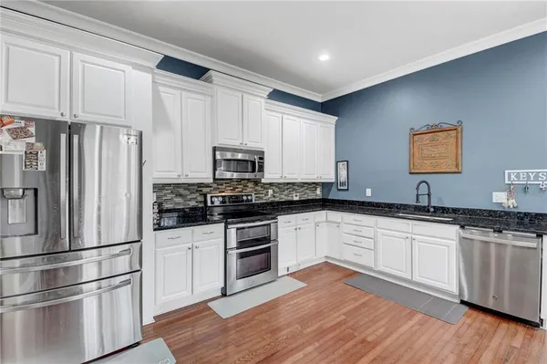 a kitchen with granite countertop white cabinets and stainless steel appliances