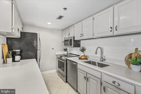a kitchen with stainless steel appliances granite countertop a sink a stove and a refrigerator