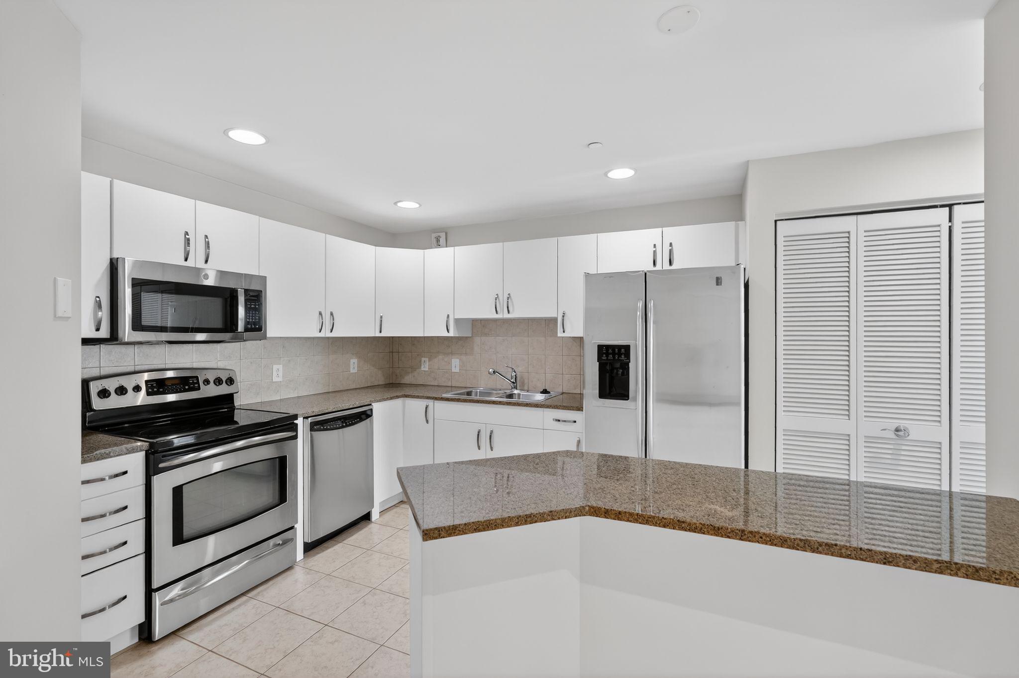 901 North Penn Street, Unit R1001 Philadelphia, PA 19123 - Photo 8 of 24 a large white kitchen with stainless steel appliances granite countertop a stove a sink and a refrigerator
