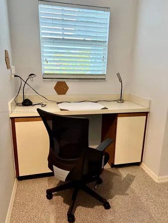 a view of a workspace with furniture and a window