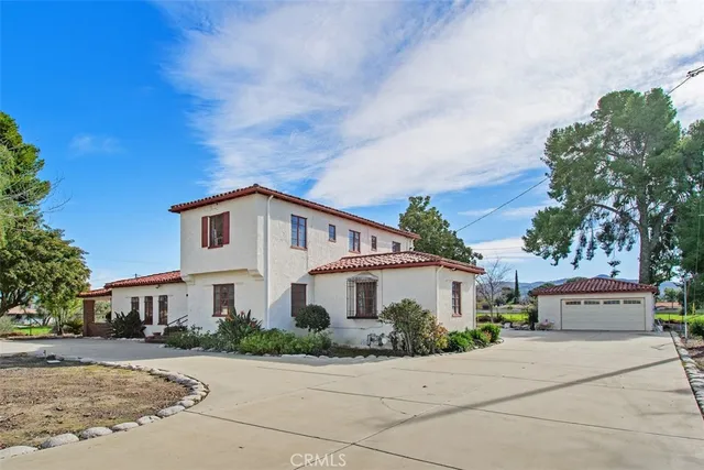 a view of a white house with a yard and potted plants