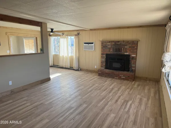 a view of an empty room with wooden floor fireplace and a window