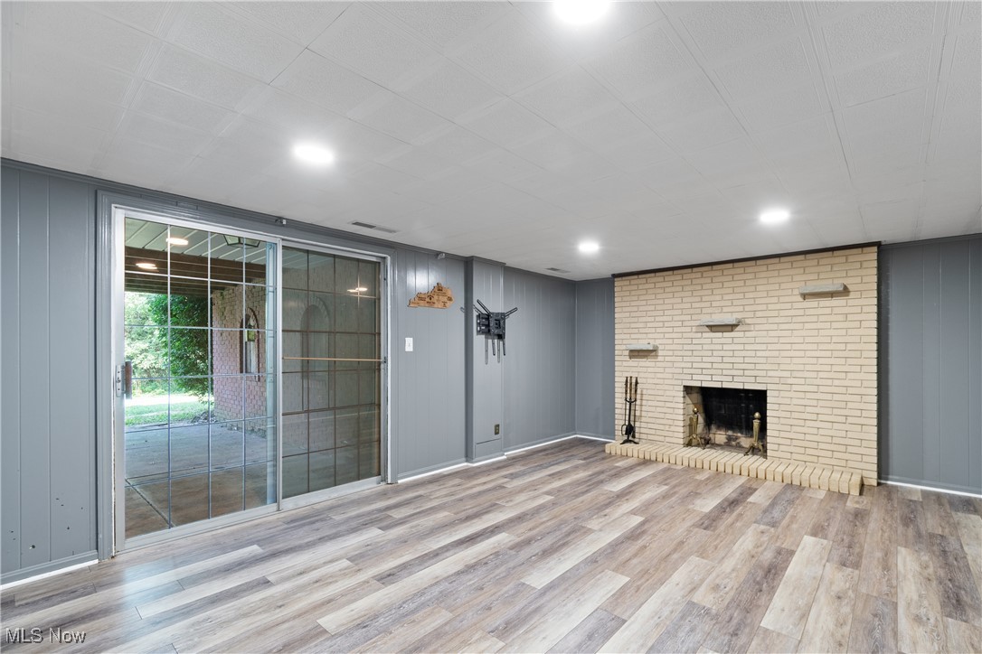 515 Oneida Avenue Northwest Canton, OH 44708 - Photo 25 of 28 Unfurnished living room with a fireplace, light wood-style floors, and wood walls