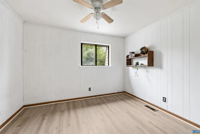 an empty room with windows and fan