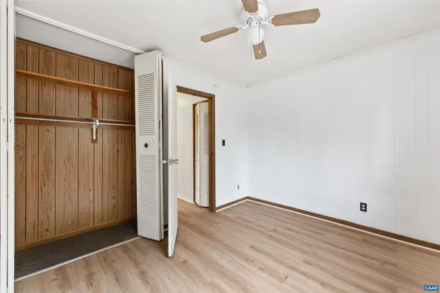 a view of empty room with wooden floor and fan