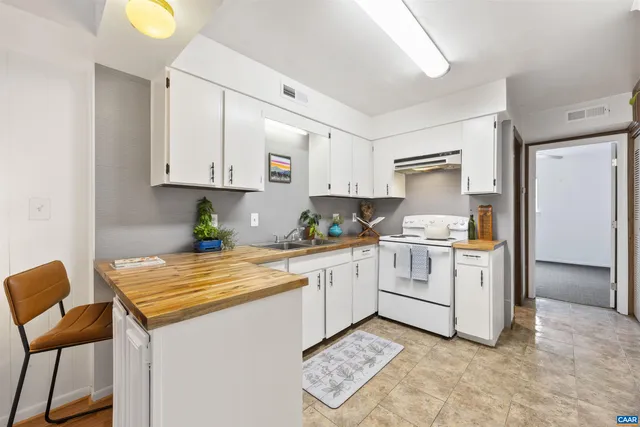 a kitchen with granite countertop a white stove top oven cabinets and a refrigerator