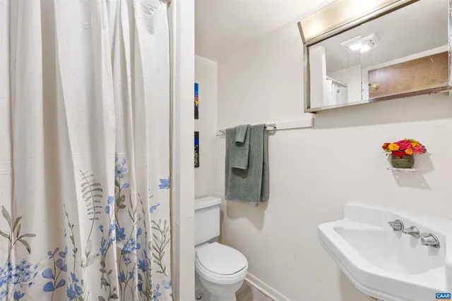a bathroom with a toilet sink and shower curtain