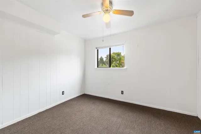 an empty room with a window and a fan