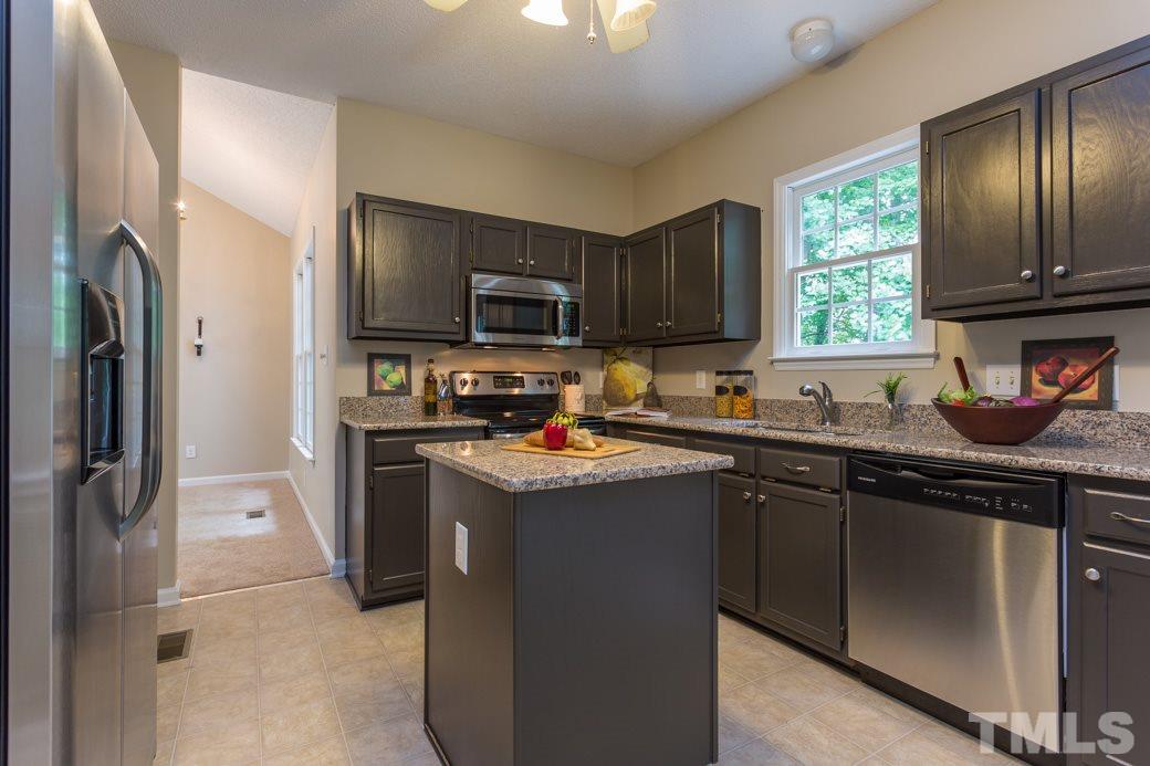 12304 Hartwick Court Raleigh, NC 27613 - Photo 3 of 14 a kitchen with stainless steel appliances granite countertop a refrigerator a sink a stove a microwave and wooden cabinets