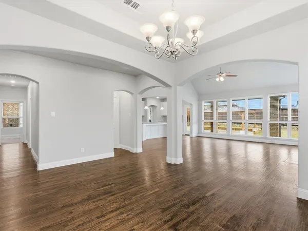 a view of an empty room with wooden floor and a large window