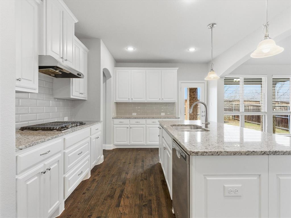 2217 Commons Way Prosper, TX 75078 - Photo 16 of 37 Kitchen with pendant lighting, light stone countertops, white cabinetry, arched walkways, and recessed lighting