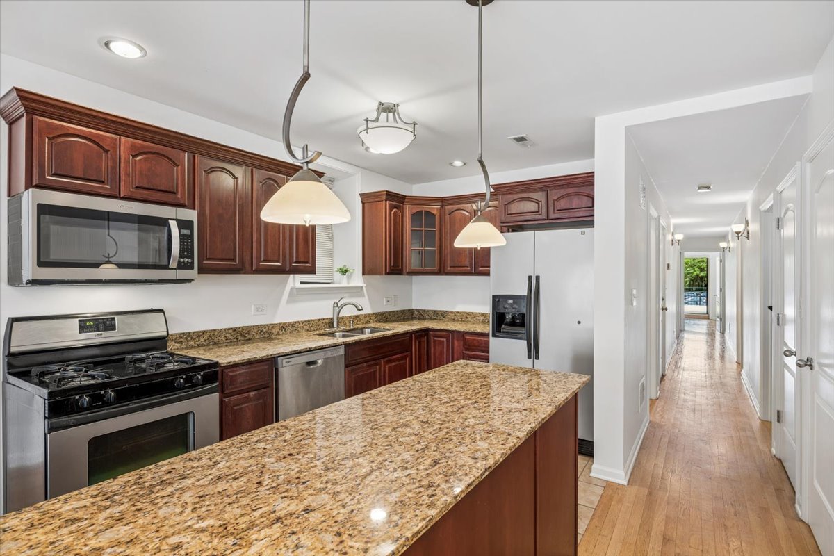 2363 East 70th Street, Unit 1 Chicago, IL 60649 - Photo 13 of 26 a kitchen with stainless steel appliances granite countertop wooden cabinets a stove a sink and a wooden floors