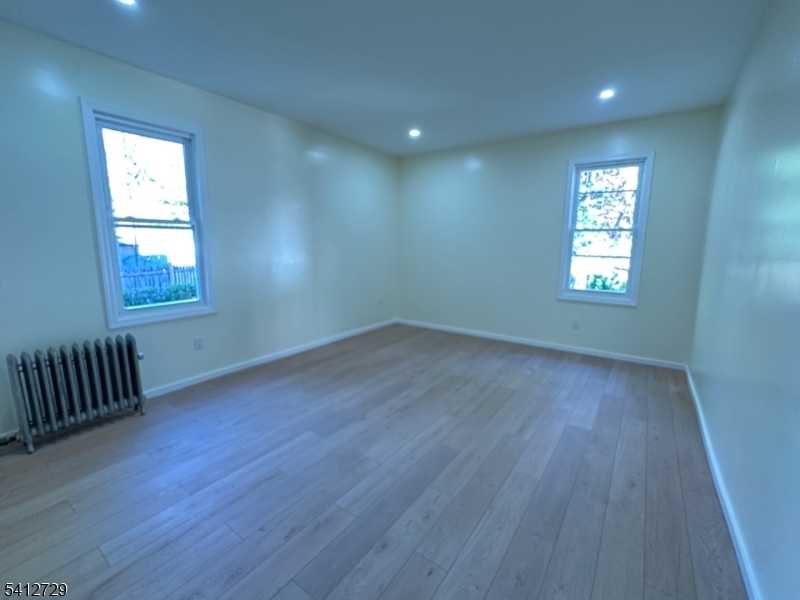 22 Cummings Street, Unit 3 Irvington, NJ 07111 - Photo 2 of 7 an empty room with wooden floor and windows