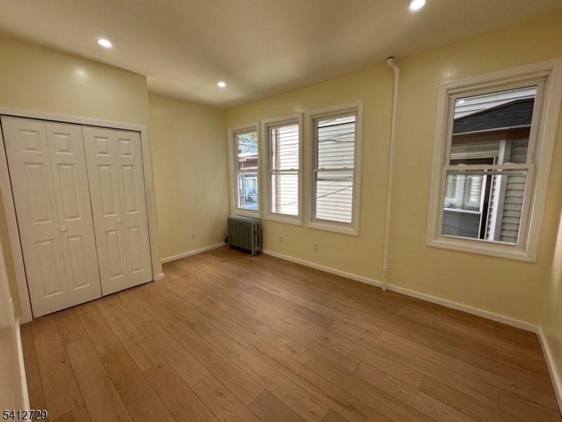 22 Cummings Street, Unit 3 Irvington, NJ 07111 - Photo 6 of 7 a view of an empty room with a window and wooden floor