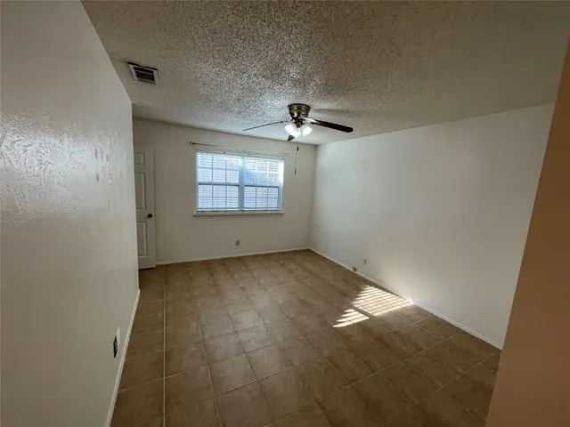 an empty room with chandelier fan and windows