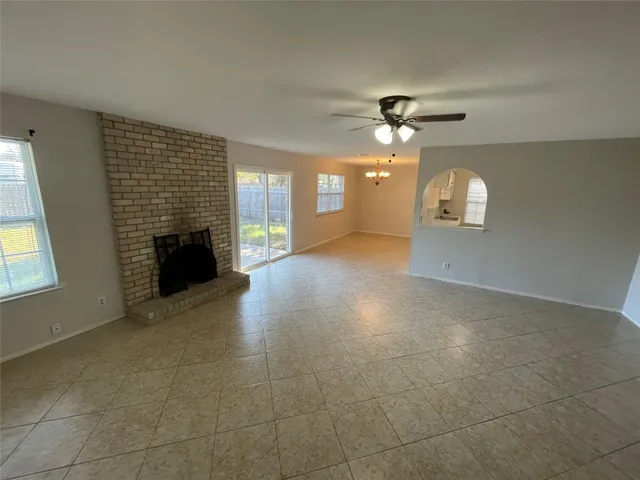 a view of a livingroom with a fireplace a ceiling fan and windows