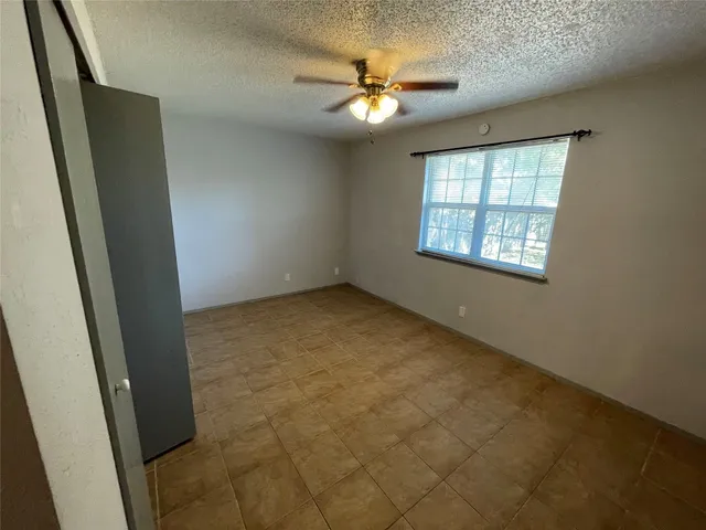 an empty room with windows and fan