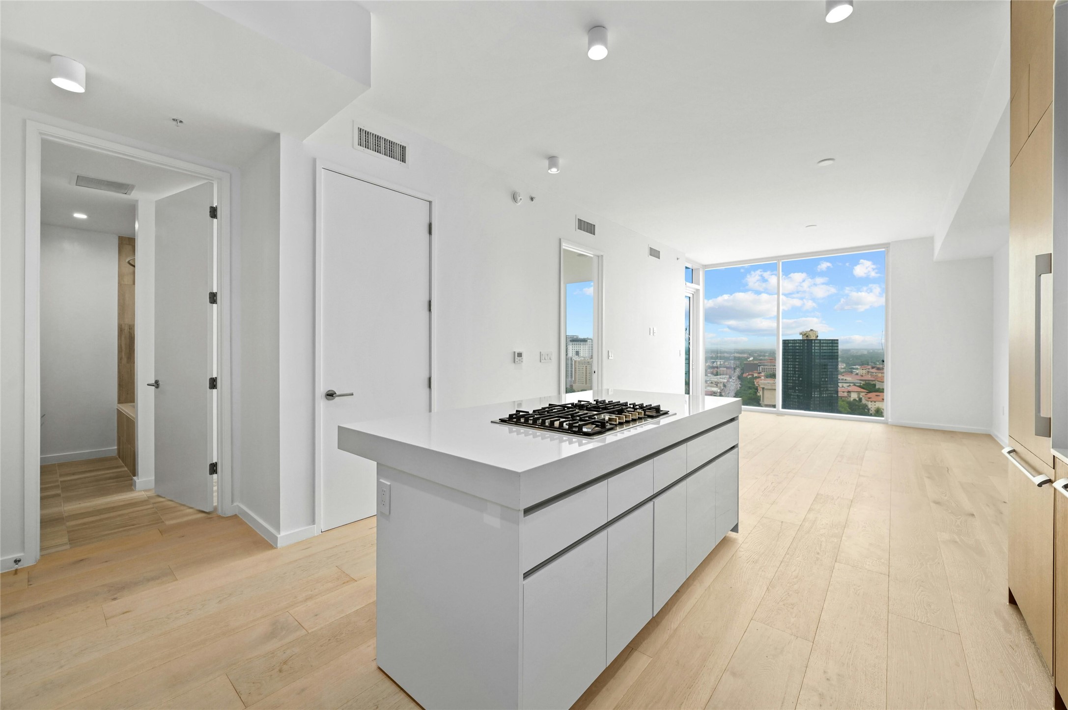 313 West 17th Street, Unit 2103 Austin, TX 78701 - Photo 3 of 39 Expansive open-concept design with a Silestone® island and integrated Bosch® appliances, blending kitchen and living seamlessly. Floor-to-ceiling windows showcase dramatic skyline and UT Tower views, filling the space with natural light. Wide-plank oak floors add warmth and continuity throughout.