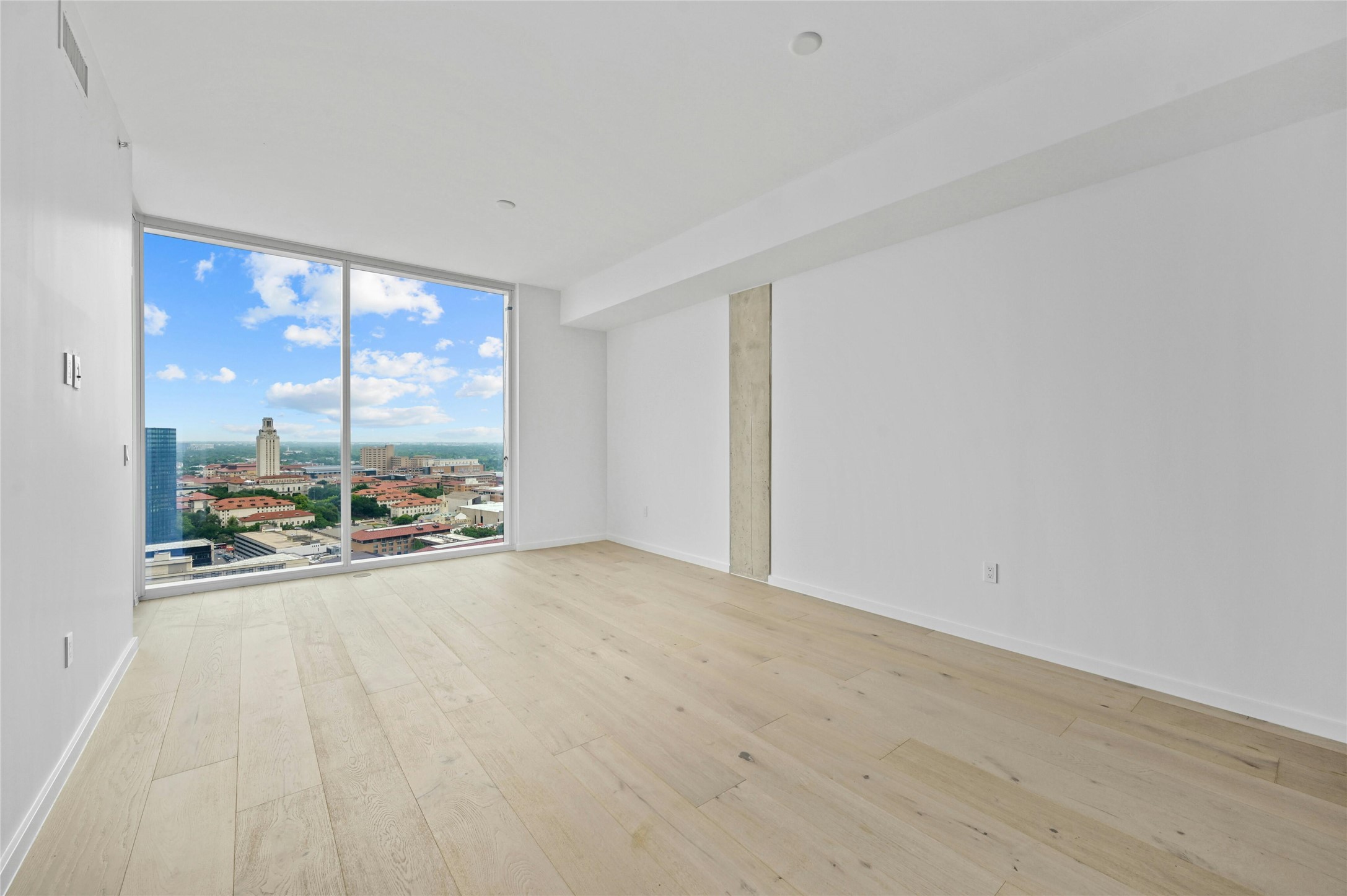 313 West 17th Street, Unit 2103 Austin, TX 78701 - Photo 36 of 39 An open floor plan and floor-to-ceiling glass panels offering stunning city views, including the UT Campus building. Modern furnishings and neutral tones create a stylish and inviting space perfect for relaxation and enjoying the urban scenery.