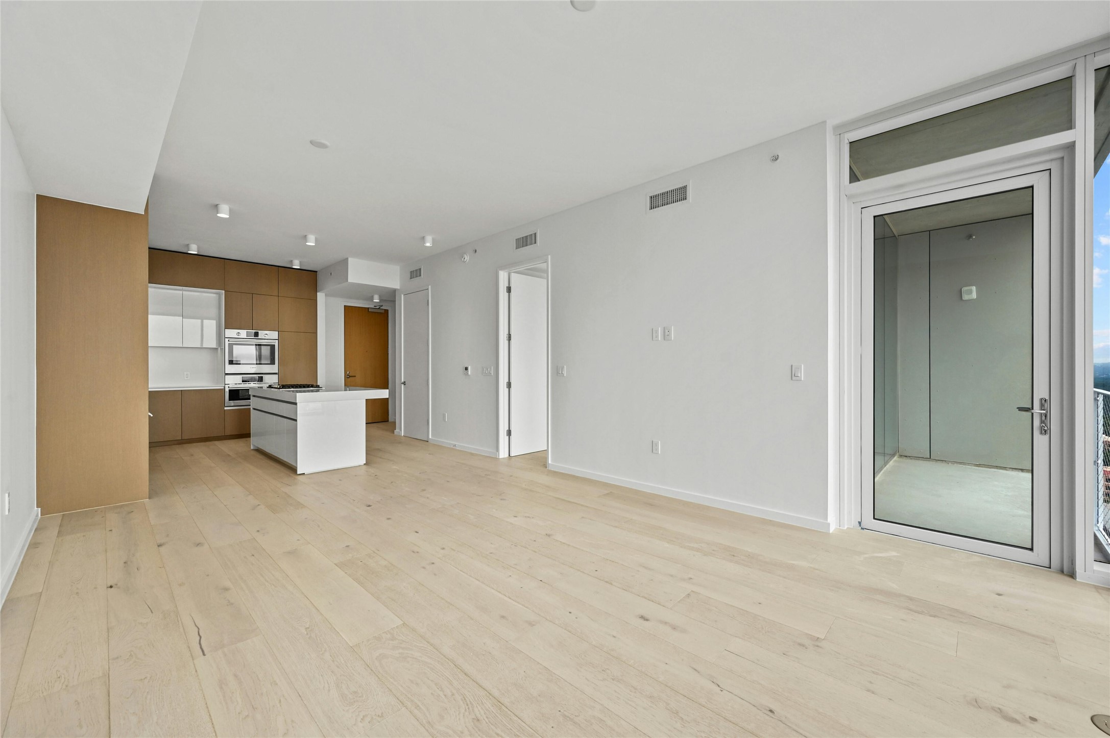 313 West 17th Street, Unit 2103 Austin, TX 78701 - Photo 6 of 39 Open-concept living and dining anchored by a sleek Rhode Partners–designed kitchen with Silestone® island, integrated Bosch® appliances, and custom cabinetry. Wide-plank oak floors carry throughout, and sliding glass doors extend the living space onto a private balcony for indoor-outdoor enjoyment.