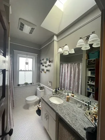 a bathroom with a granite countertop sink a toilet a mirror and shower