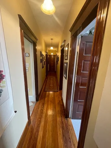 a view of a hallway with wooden floor and stairs
