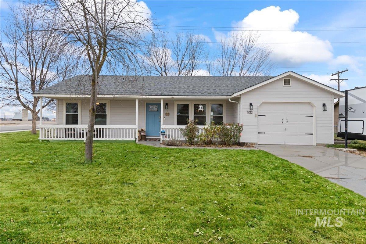 Ranch-style home featuring a porch, a garage, a shingled roof, and a front yard